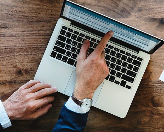Hands pointing at laptop computer
